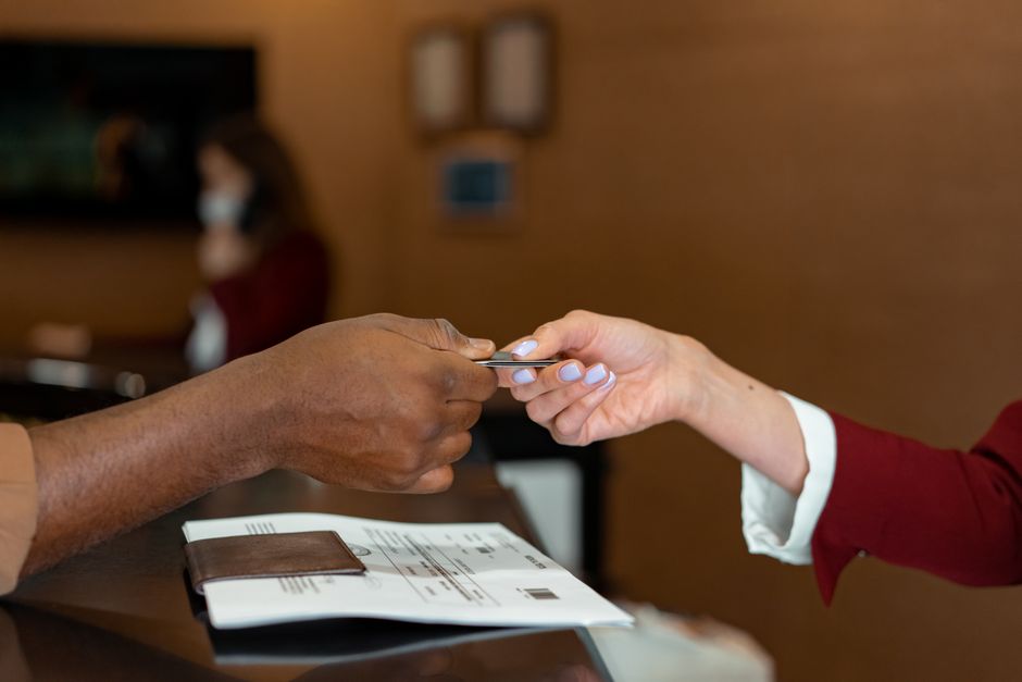 Economia do Turismo — Close-up of a hotel receptionist receiving a credit card from a guest, highlighting a transaction at