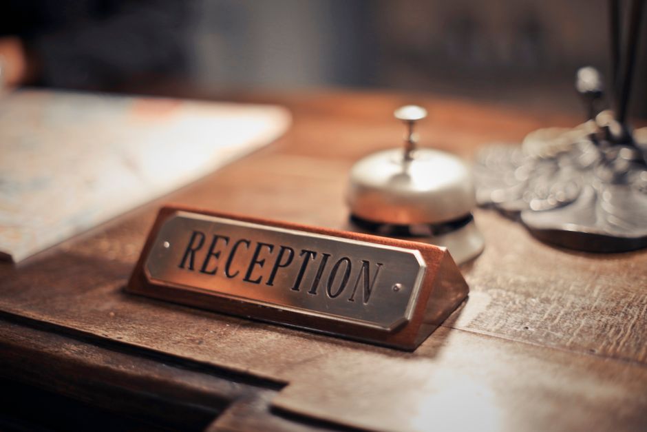 Economia do Turismo — Close-up of a hotel reception desk showcasing a service bell and signage, emphasizing hospitality.